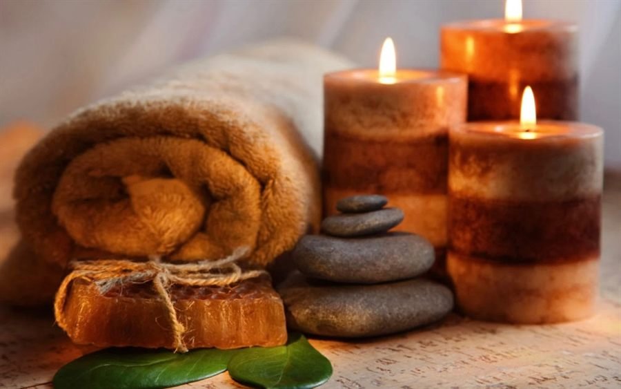 Rolled towels, warm stones and lit candles in a spa treatment room