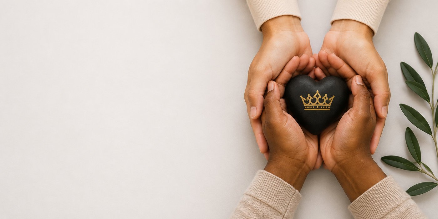 Two pairs of hands gently cradling a black stone heart marked with a gold crown, beside an olive branch